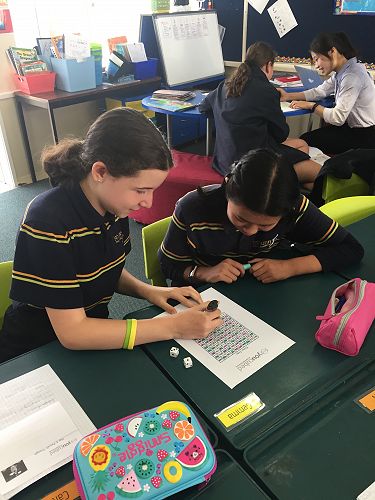 Caitlin and Kelly colour patterns in a hundred chart showing multiples of a number they have rolled.