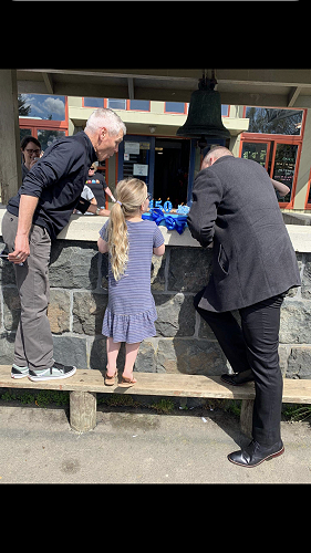 Mr. Reid, Mia, and Mr. Clarke blow out the candles on the cake