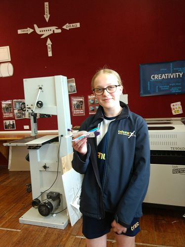Learning to fly: Maddie Ellis is ready to test her airplane. In the background is a diagram of the four forces affecting flight.