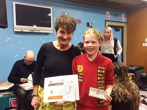 Lily receiving her prize pack from Kate de Goldi