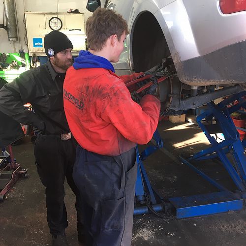 Archie Calder replaces brake pads at Automotive Solutions under the watchful eye of his mentor