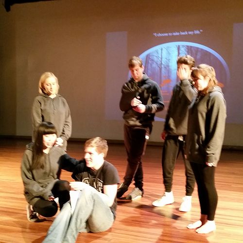 Stage Manager Alfie Richardson (sitting centre), helping the Greek Chorus during rehearsal of one of their scenes